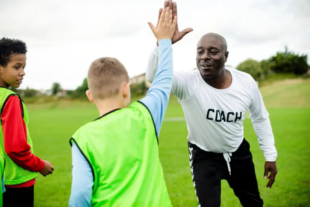 Trainer klatscht mit Spielern ab während des Trainings