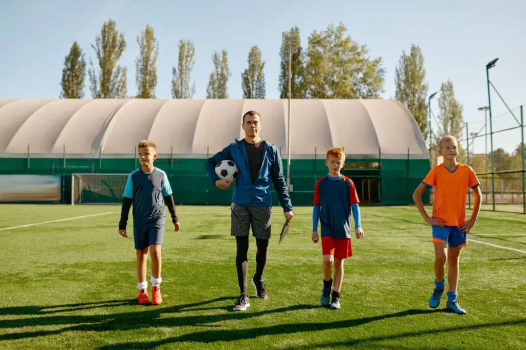 Trainer mit seinem Jugendteam läuft über den Platz